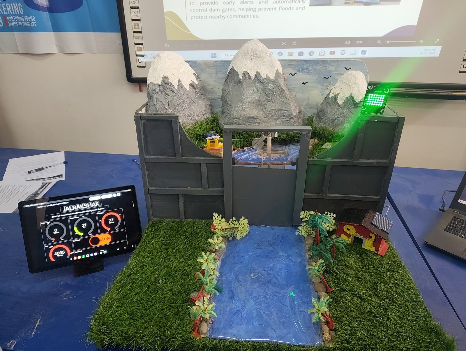 JalRakshak working prototype with mountains, dam, river and tablet showing live dashboard